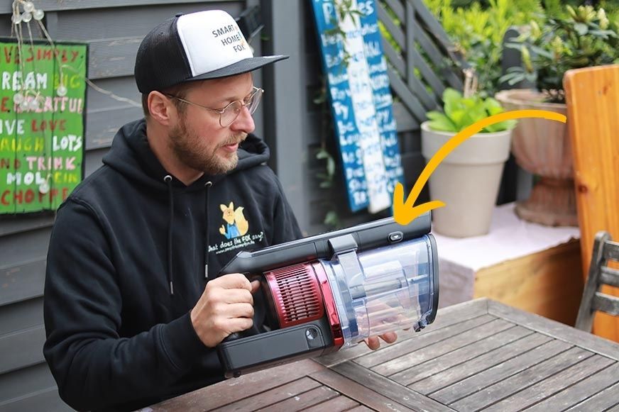 Man sieht den Knopf zum Öffnen des Schmutzbehälters.